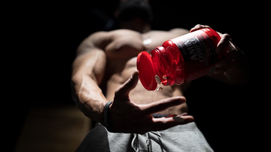 Shirtless muscular man pouring protein supplements from a bottle, showcasing fitness and strength.