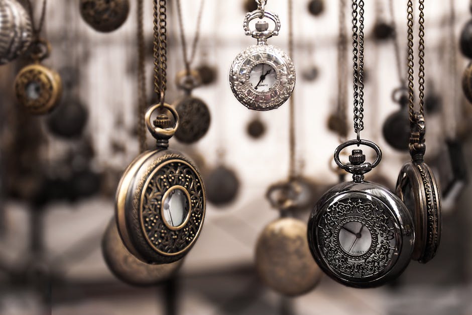 Close-up of antique pocket watches with intricate designs hanging in a blurred vintage setting.